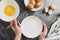 Whipping white eggs with whisk, in a palte. Top view of woman& x27;s hands mixing eggs, cooking pastry