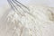 Whisk lying in white wheat flour