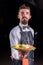 Whiskered waiter helpfully serves plate with prepared dish at a festive event.