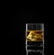 Whiskey glass with golden alcohol and ice cube