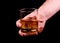 Whiskey glass in a hand of a man on black background, brandy in a glass