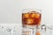 Whiskey glass with ice and dynamic water droplets on a white background