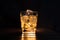 whiskey with ice cubes in glass on dark background and wood table, relax with whisky concept on the warm atmosphere