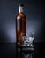 Whiskey with ice cubes in glass near bottle on black background, cold atmosphere