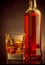 Whiskey with ice cubes in glass near bottle on black background, warm atmosphere