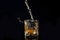 Whiskey pouring into glass with ice isolated on black background