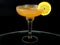 A whisky sour in a coupe glass with a lemon wagon wheel garnish.