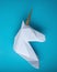 White 3d papercraft model of unicorn head on blue background. Minimal art concept