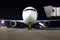 White aircraft on the parking area in the airport at night, front view