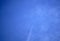 White airliner transports passengers while it pulling white contrails in dark blue cloudy sky