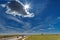 White airplane footprints over the highway and the blinding sun in the blue sky.