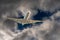 White airplane jet flying through a hole in dark dangerous and dramatic storm clouds