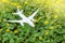 White airplane model on flower fresh green leaves background. Clean green energy, biofuel for aviation industry.