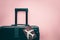 White airplane model, Thai passport and black luggage on pink background