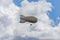 White airship of a soft system with stabilizers and a motor hovers in the sky