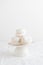 White airy zephyr or marshmallow shells on a white cake stand on a white table, space for text