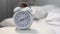 White alarm clock on night table near bed, time management, sleeping hours