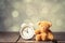 White alarm clock and teddy bear toy on wooden table