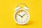 White alarm clock on a yellow background