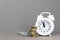 White alarmclock with Coins stack and stack of one hundred dollar bills on grey background. Interest rate and dividend concept,