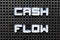 White alphabet with word cash flow on black pegboard background