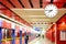 White analog clock in red urban subway station