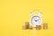 White analog clock white blurred stack of coins on vivid yellow background for business and  finance concept