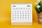 White April 2023 calendar with potted plant on yellow background.