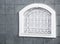 White arched window with openwork lattice on gray tiled wall