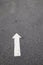 White arrow on cracked asphalt surface. Concept traffic