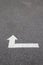 White arrow on cracked asphalt surface. Concept traffic