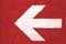 White arrow on red background: white directional arrow manually painted on a red wooden signboard