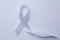 White awareness ribbon on white background, top view