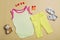 White baby bodysuit for a girl on a beige background with baby shoes, a teddy bear, yellow pants, a mockup of a bodysuit for