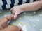 White baby holding finger of black adult hand