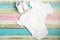 White baby onesie and sneakers over pastel wooden background. Good for insert your design. Mock up.