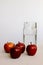 On a white background are four juicy red apples and a jug with crystal clear water