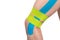 On a white background, knee with Kinesio tapes pasted on to relieve stress and protect against damage when playing sports