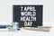 On a white background lies a stethoscope, a pen and a black notebook with the inscription - 7 APRIL WORLD HEALTH DAY