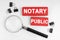 On a white background, a magnifying glass and red plates with the inscription - NOTARY PUBLIC