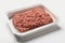 On a white background, a plastic tray holds raw, fresh, minced beef