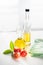 On a white background vegetable olive oil in a glass decanter. Nearby are slices of tomatoes and a green leaf.