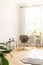 White background wall with empty space in a high ceiling room interior with a rattan and metal chair in the corner and side tables