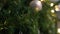 White ball hanging from a Christmas tree with snow falling