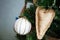 A white ball wrapped in a waxed cord and a heart sewn from sacking hang on an artificial Christmas tree decorated in rustic style