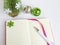 White ballpoint pen on the opened notebook in a pink cover and Christmas balls on a white background, Christmas and New Year ideas