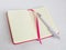 White ballpoint pen on the opened notebook in a pink cover on a white background