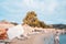 White Bank Card In Woman Hand On Background Of Hotel Beach, Family Comes Out Of Sea, Moraitika, Corfu, Greece. The Concept Of