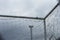 White bar of football goal with broken and messy white net seeing a pylon of stadium lighting ready for the night time.