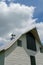 White barn with metal roof set against dramatic cloud and blue sky